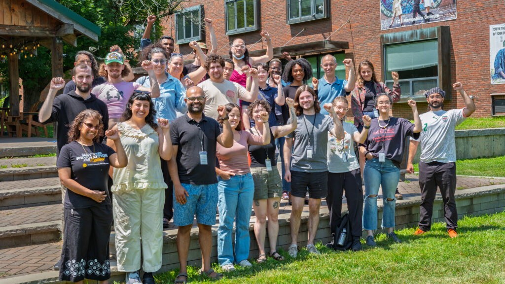 Summer institute facilitators and participants with their fists raised outside Hampshire College